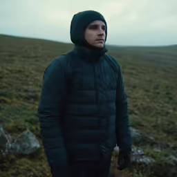 a man standing in the middle of the grass covered field