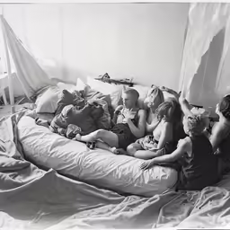 black and white photo of a group of people on a bed