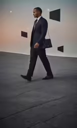 man in black and white walking on concrete next to abstract shapes