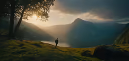 man standing on hill overlooking a lake and mountains