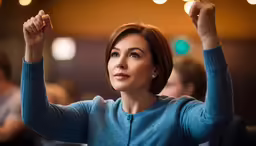 a woman raising her fist up in the air with people sitting in the back