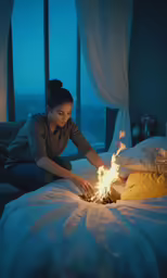 a woman sitting on a bed with a small fire