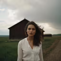 a woman posing in front of a small wooden house