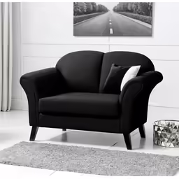 a chair with pillows next to a vase on the floor