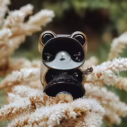 a little black and white bear figurine sitting on some branches