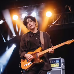 a man standing in front of an amp with an orange guitar