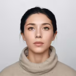 a woman with light brown hair is wearing a neutral coat