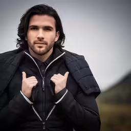 the man is making his fist gesture while wearing a jacket
