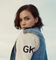 a woman with short hair in an oversized denim jacket