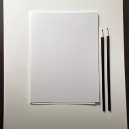 an empty sheet of paper with two pencils sitting next to it