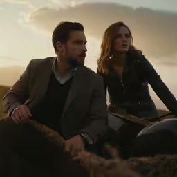 the young couple are sitting on the hay