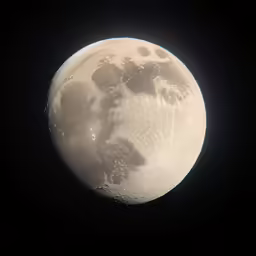 the moon with its shadow lit up and the night sky