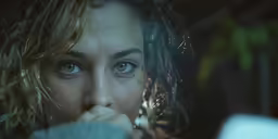 the young woman stares at her reflection in the mirror