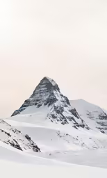 a snowy mountain with snow capped peaks in the distance