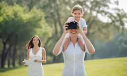woman holding up a child while she takes pictures of her and the other girl