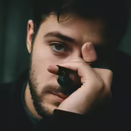 a close up of a man with his hands to his face