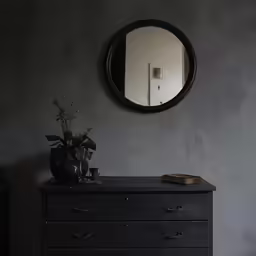 a mirror sitting above a dresser with flowers