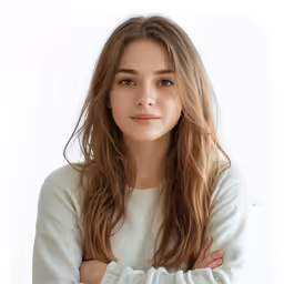 young woman with long hair in white top standing with arms crossed
