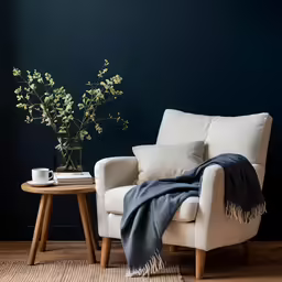 a chair next to a table with flowers and teacup on it