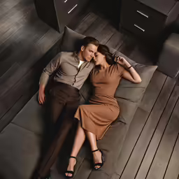 a woman and man lying on the couch at night