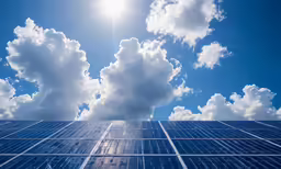the sun shining through clouds over a solar plant