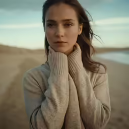 a girl poses for a photo in a sweater by the beach