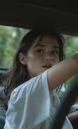 a woman sits in a car with her arm out the window