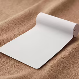 an empty white paper is laying on a light brown fabric