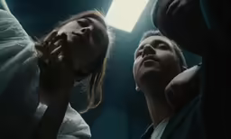 two people standing in a dark room staring at something
