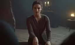 a woman in a dark room holds her hand over the edge