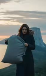 a woman is standing on the top of a mountain with a blanket around her