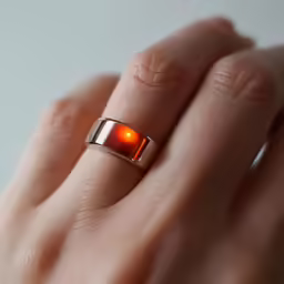 the hand is holding an orange glowing ring