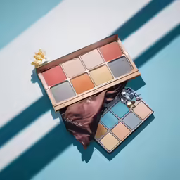 a makeup set sits on a table, next to the contents of a brown purse