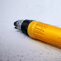 the orange and black tool is laying on the white surface