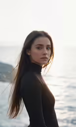 a woman wearing a black outfit is posing on a rocky shore