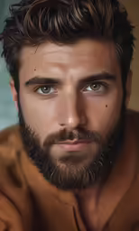 a close up photo of a man with beard wearing a brown shirt