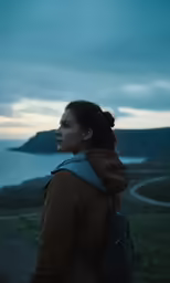 a woman is standing on the hill overlooking a lake