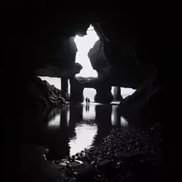 a man standing in a cave with the sun coming out