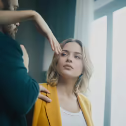 a woman with her hand on her hair is standing in front of a man who is holding her hand up