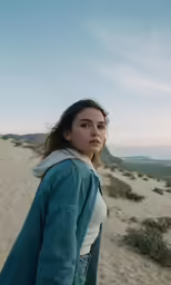 a woman walking on the beach with a jacket over her head