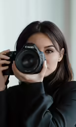 a woman taking pictures with a camera close to her face