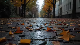 a walkway covered in yellow leaves under some building