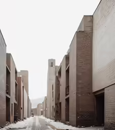 an empty street lined with brick buildings covered in snow