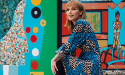 a woman posing for a photo with a colorful artwork behind her