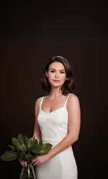 a beautiful woman in white dress holding a green bouquet