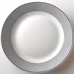 a white and silver empty plate sitting on top of a counter