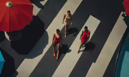 three women walk down the street while wearing bathing suits
