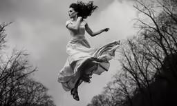 a woman is in mid - flight and a dress is on the ground