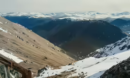 a mountain top with snow covered mountains and shrubs