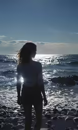 the woman is on the beach looking out to sea